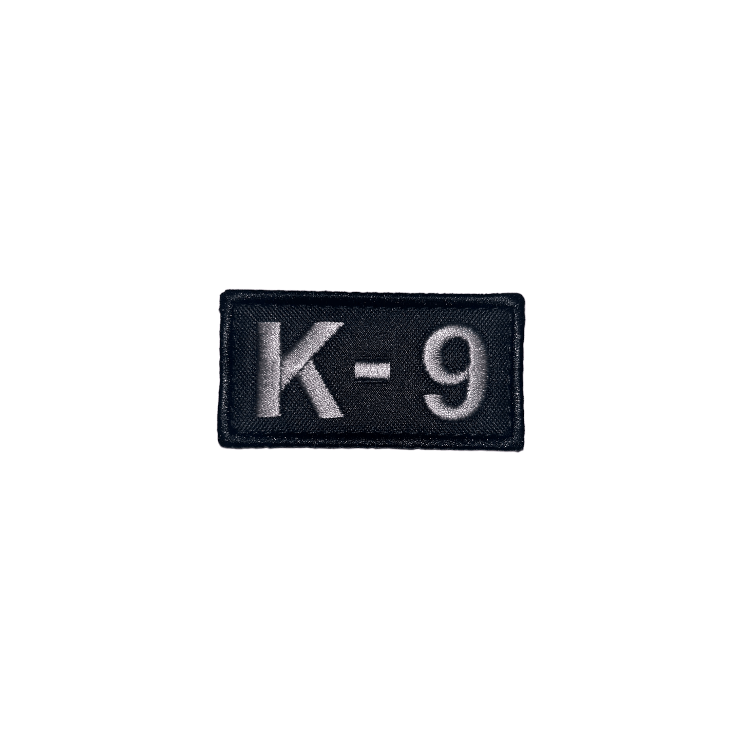 Embroidered patch featuring 'K-9' in light gray, perfect for dog vests, dimensions 2 3/4" x 1 3/8", with hook and loop.