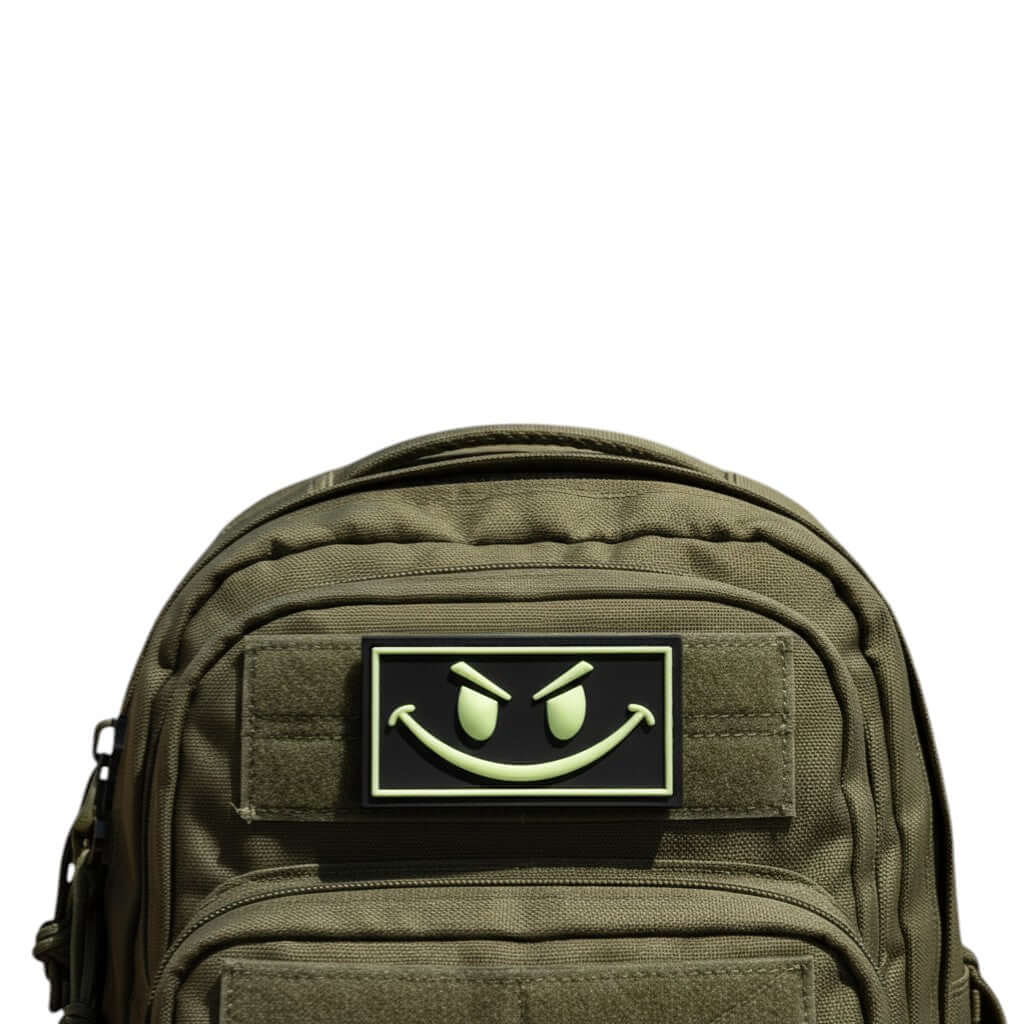 Trooper Clothing black PVC patch with glow-in-the-dark yellow smiley face and border. Hook-and-loop backing.