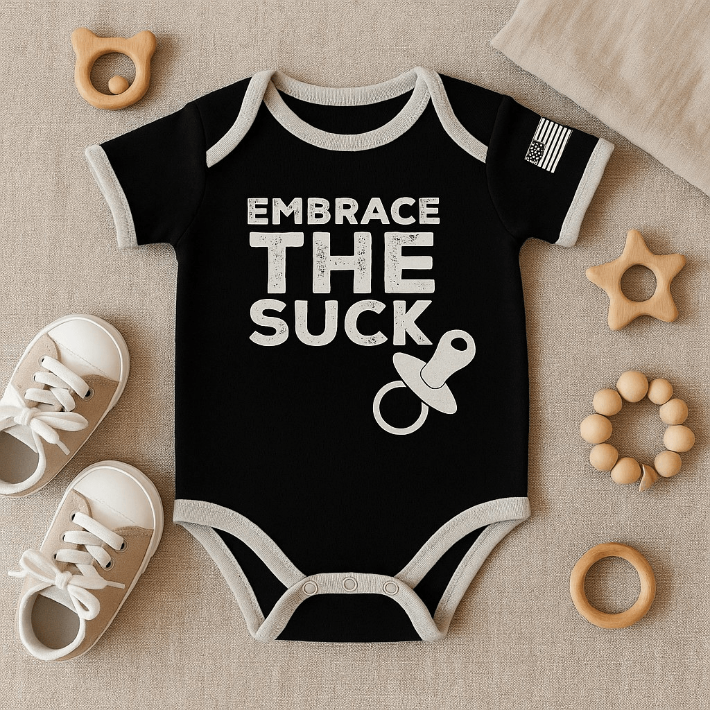 Baby Embrace the Suck bodysuit in black with American flag and pacifier design on a soft background.