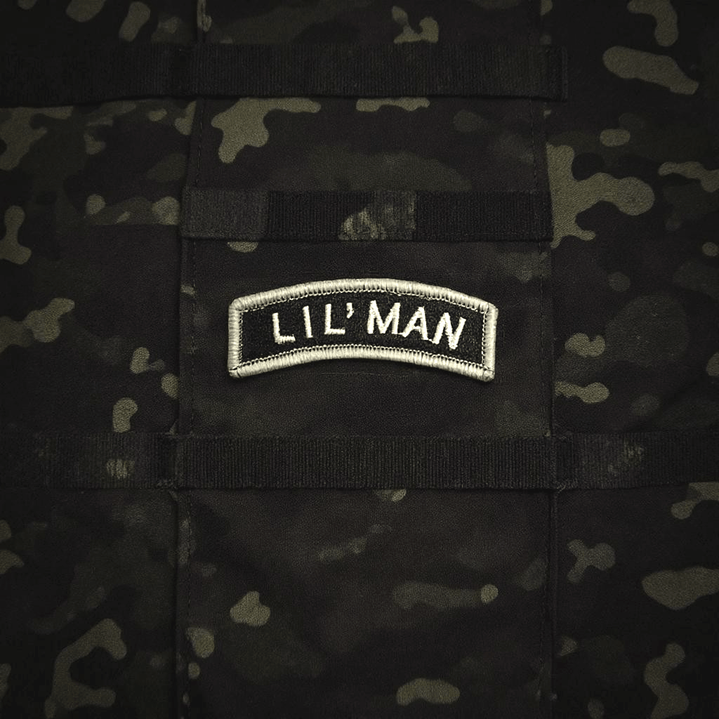 Lil' Man rocker patch in gray and black on a textured camouflage background.