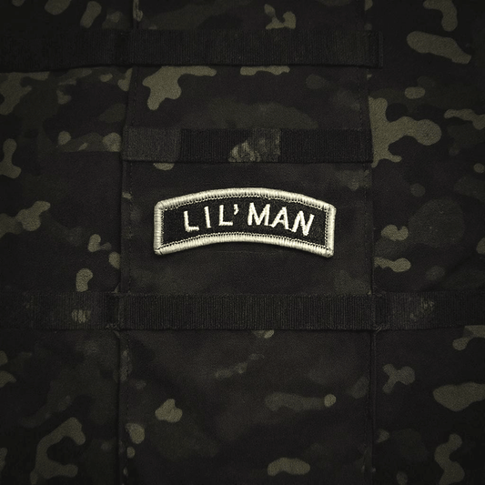 Lil' Man rocker patch in gray and black on a textured camouflage background.