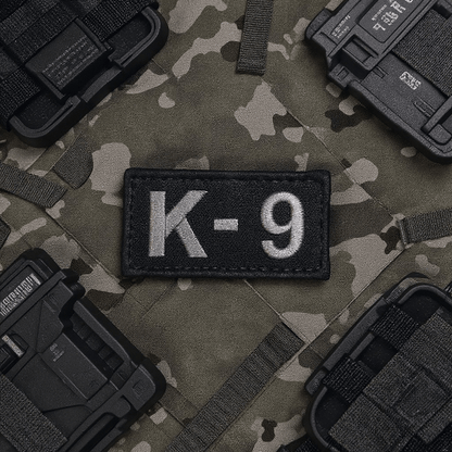 Embroidered Patch K-9 by Trooper Clothing on camo vest, featuring light gray stitching and hook and loop backing.