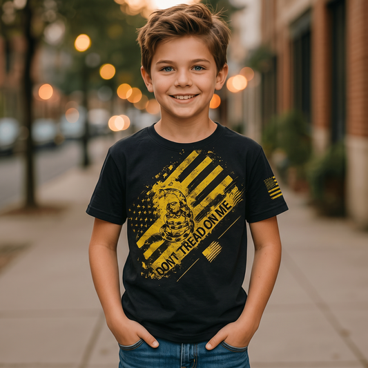 A smiling boy wearing a black Trooper Clothing youth T-shirt with a yellow Don't Tread on Me graphic and flag sleeve.